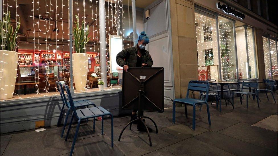 Woman packs away a table at closing time in Newcastle on 29 September