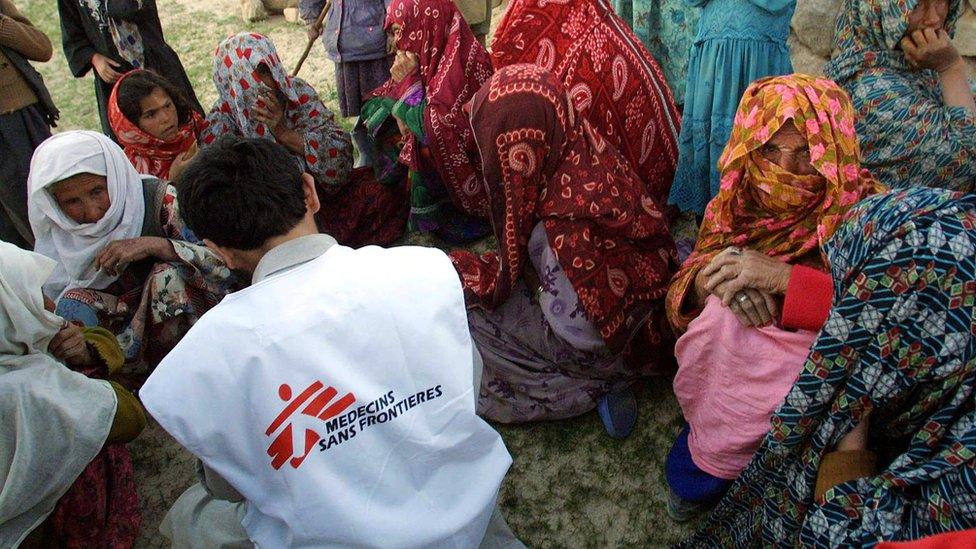 Women sit around an aid worker from Medecins Sans Frontieres waiting for their turn to receive medications a