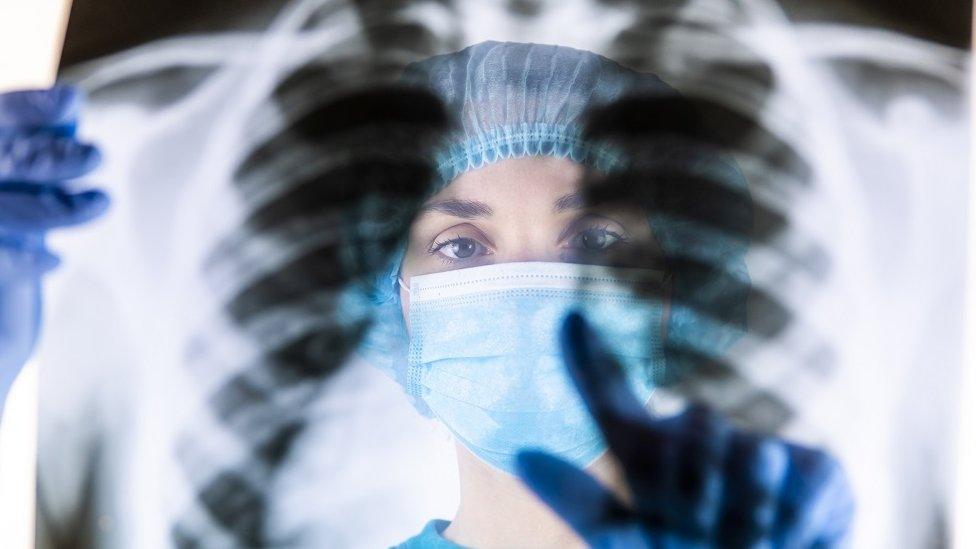 A radiologist inspects an x-ray of a person's lungs