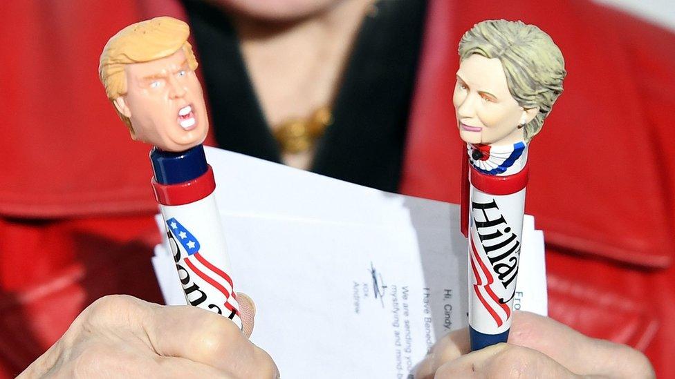 A woman holds pens in the shape of Donald Trump and Hillary Clinton