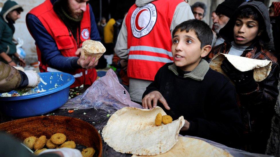 Displaced people from eastern Aleppo get food aid from the Syrian Red Crescent at a shelter in government-controlled Jibreen, Syria (30 November 2016)