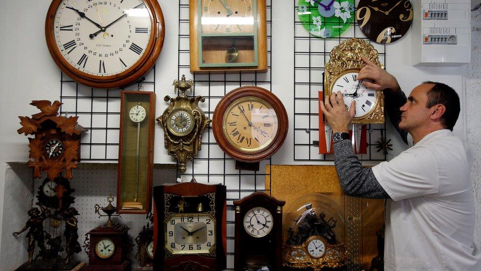 Serge Kertchef, a watchmaker, adjusts the hands on a wall clock in Marseille