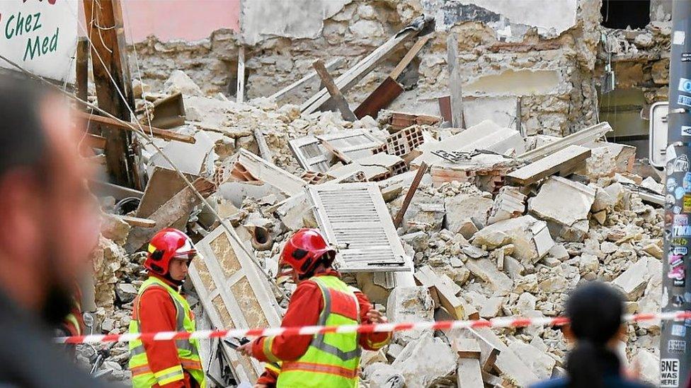 Firefighters stand afoot the rubble of the collapsed buildings in Marseille, France