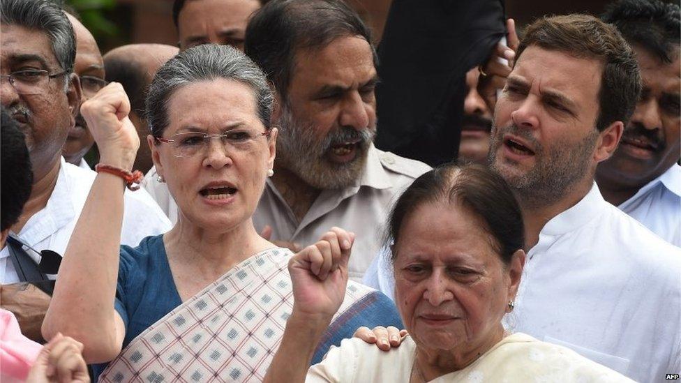 Congress Vice President Rahul Gandhi (R) and President Sonia Gandhi (C) shout slogans during a protest by Congress Party Members of Parliament at the Mahatma Gandhi statue at Parliament house in New Delhi on August 4, 2015.