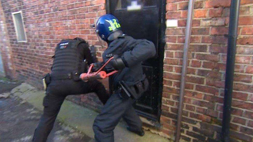 Police officers battering a door down