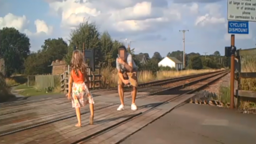 Man taking a photo of a girl on a level crossing