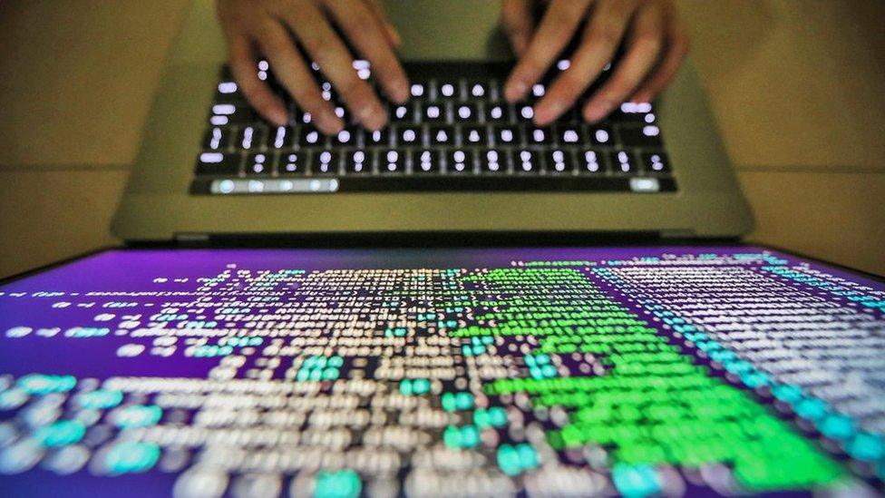 A computer programmer working on fixing Wannacry software in close up shot of screen and hands