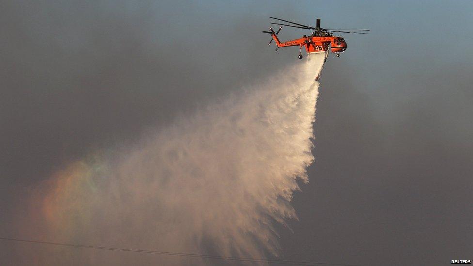 A helicopter dumps water on a brush fire in southern California