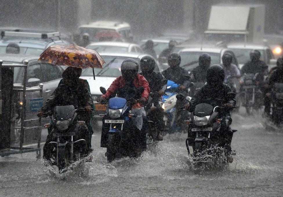 Indian commuters drive past during heavy monsoon rains in Chennai