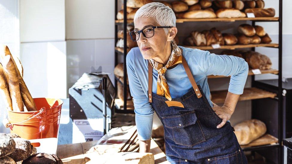 A bakery owner looks through the window of her shop