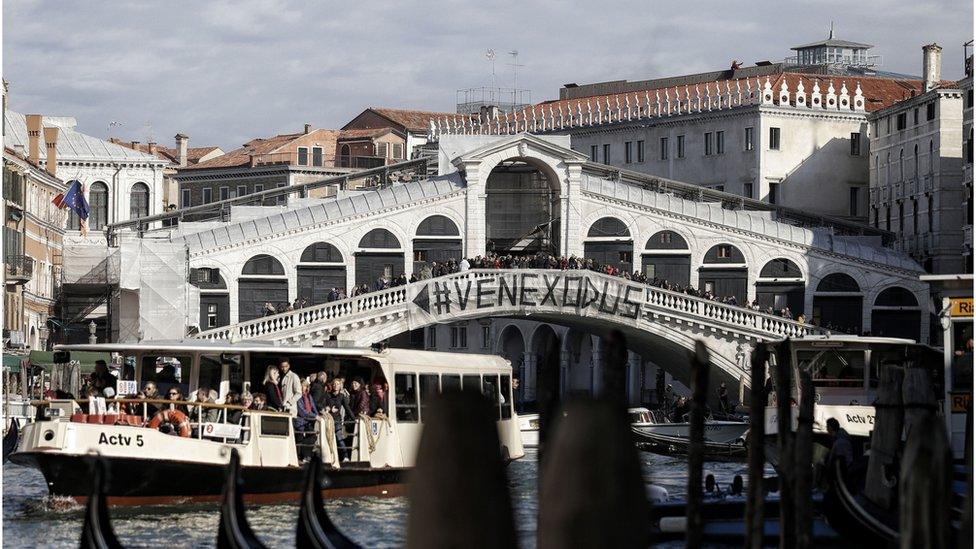 People gather on a bridge during a demonstration against the increasing number of tourists in Venice on November 12, 2016