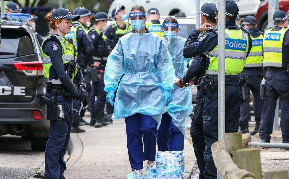 A queue of police guard a path for health care workers to walk through to the housing towers