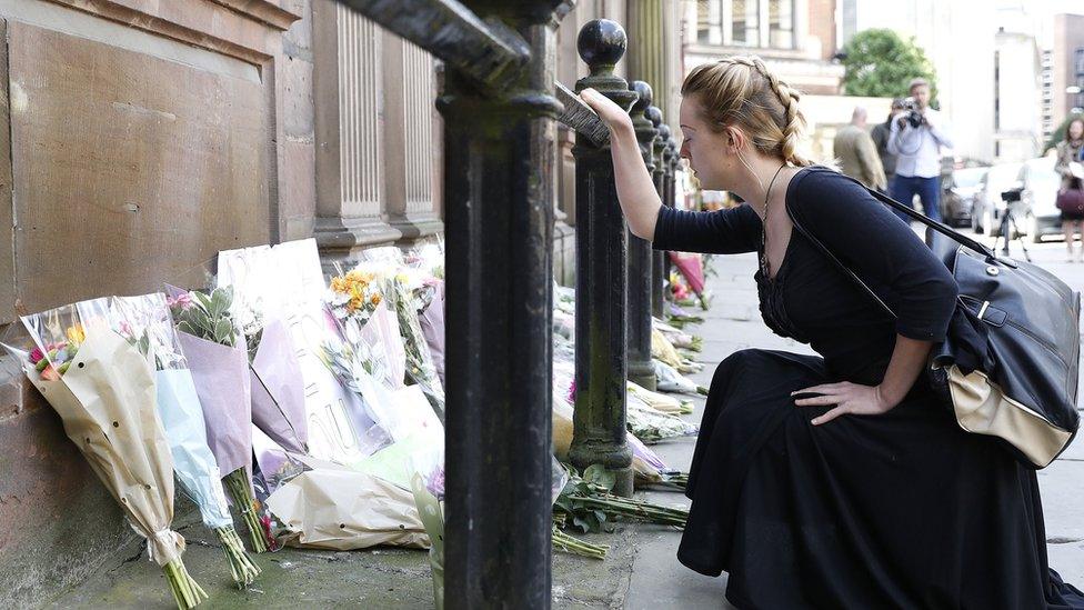 A woman prays as she views floral tributes left outside St Ann's Church, Manchester, following the Manchester Arena bomb attack