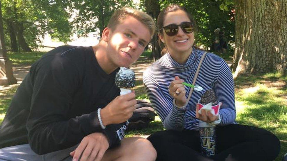 Two teenagers sit together in a park eating ice cream