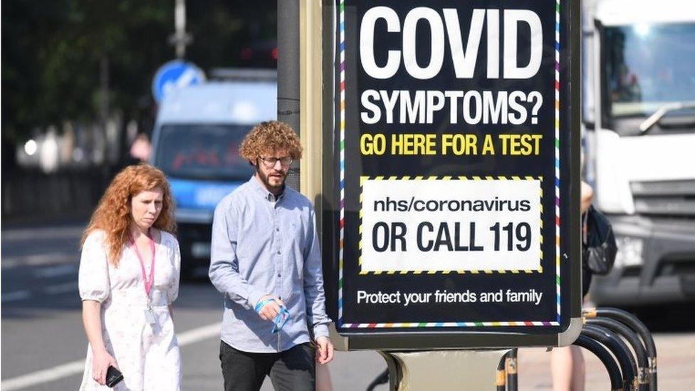 Woman and man walk past covid sign