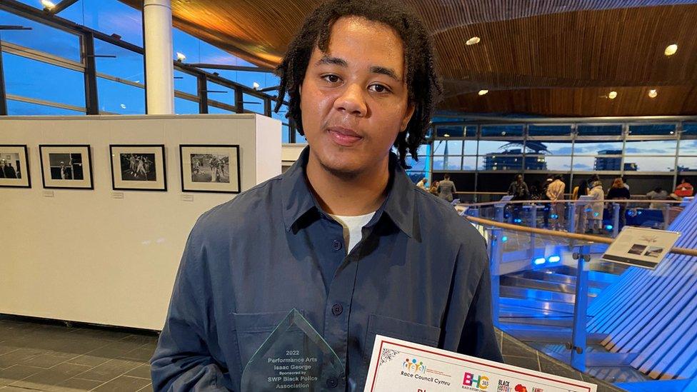 Isaac George at the Senedd holding his awards