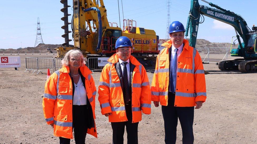 Mary Lanigan, Joonsung Lee and Ben Houchen stand at the site in front of large digging machines