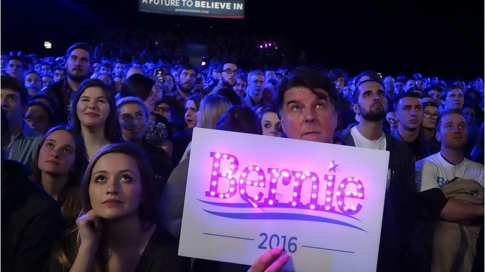 A Bernie Sanders supporter holds up a glowing sign.