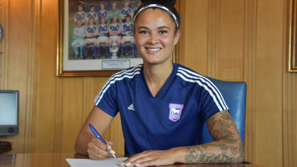 Natasha Thomas signing her contract, in her Ipswich Town training kit.