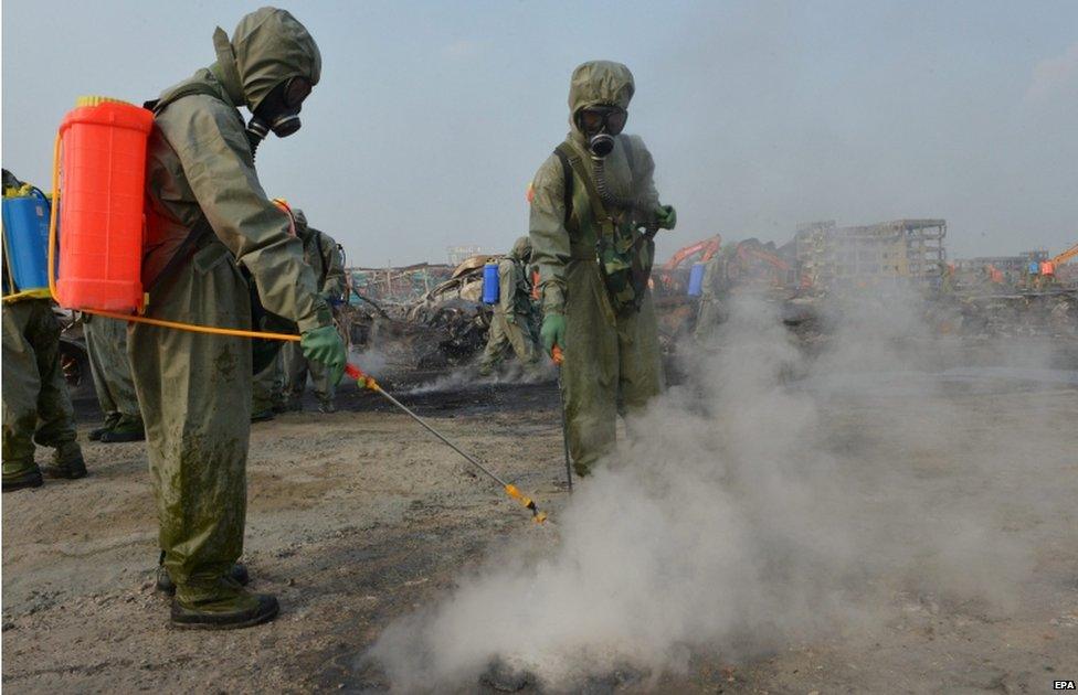 Soldiers wearing protective clothing, gas masks and respirators on a PLA chemical-defence unit work to neutralize sodium cyanide residue on the crushed vehicle wrecks in the zone of the massive chemical explosions in north China"s Tianjin Municipality 20 August 2015.