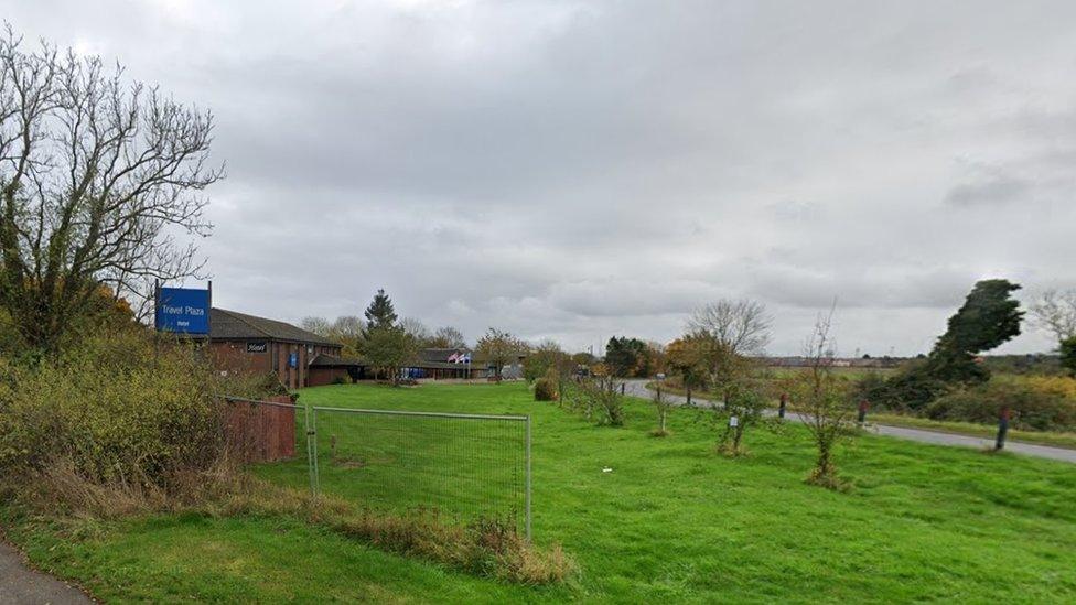 Single-storey brick roadside hotel with large grass area between the hotel and the road