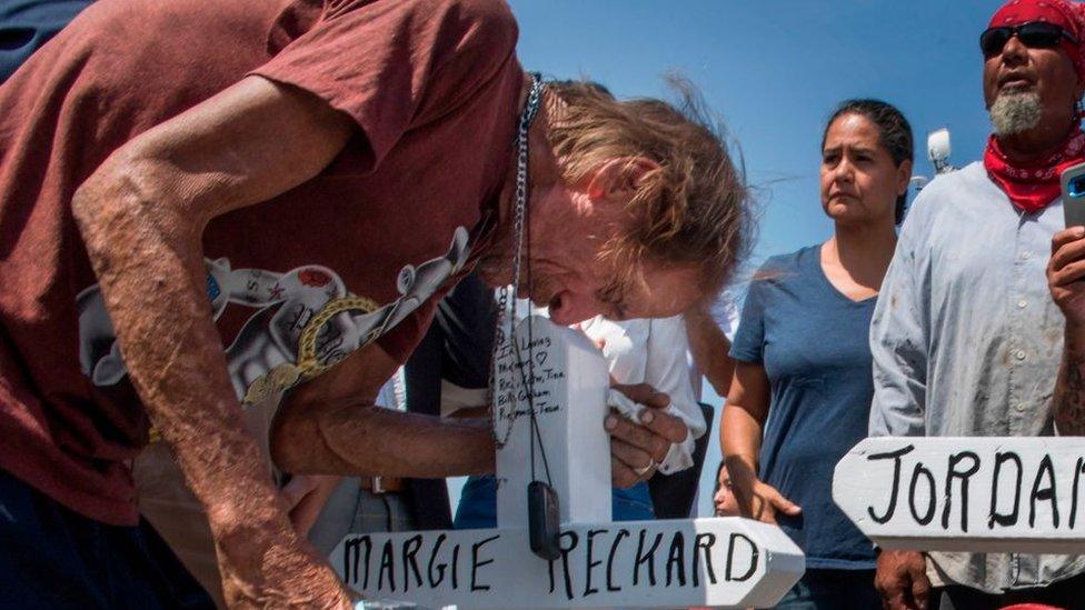 Antonio Basco kisses the cross with the name of his wife Margie Reckard at a makeshift memorial