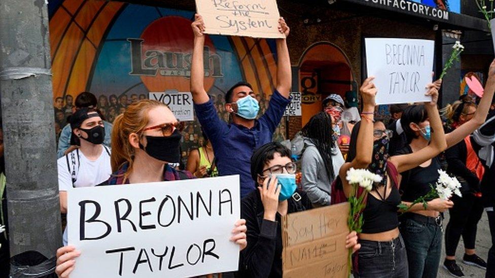 Black Lives Matter protesters hold up signs as they commemorate Breonna Taylor on what would have been her 27th birthday in Hollywood, California