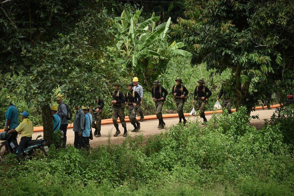 Thai soldiers run down the road leading to the Tham Luang cave