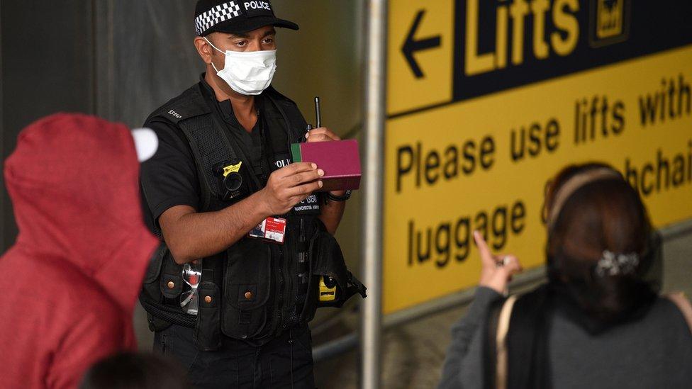 A police officer talks to passengers at Manchester Airport