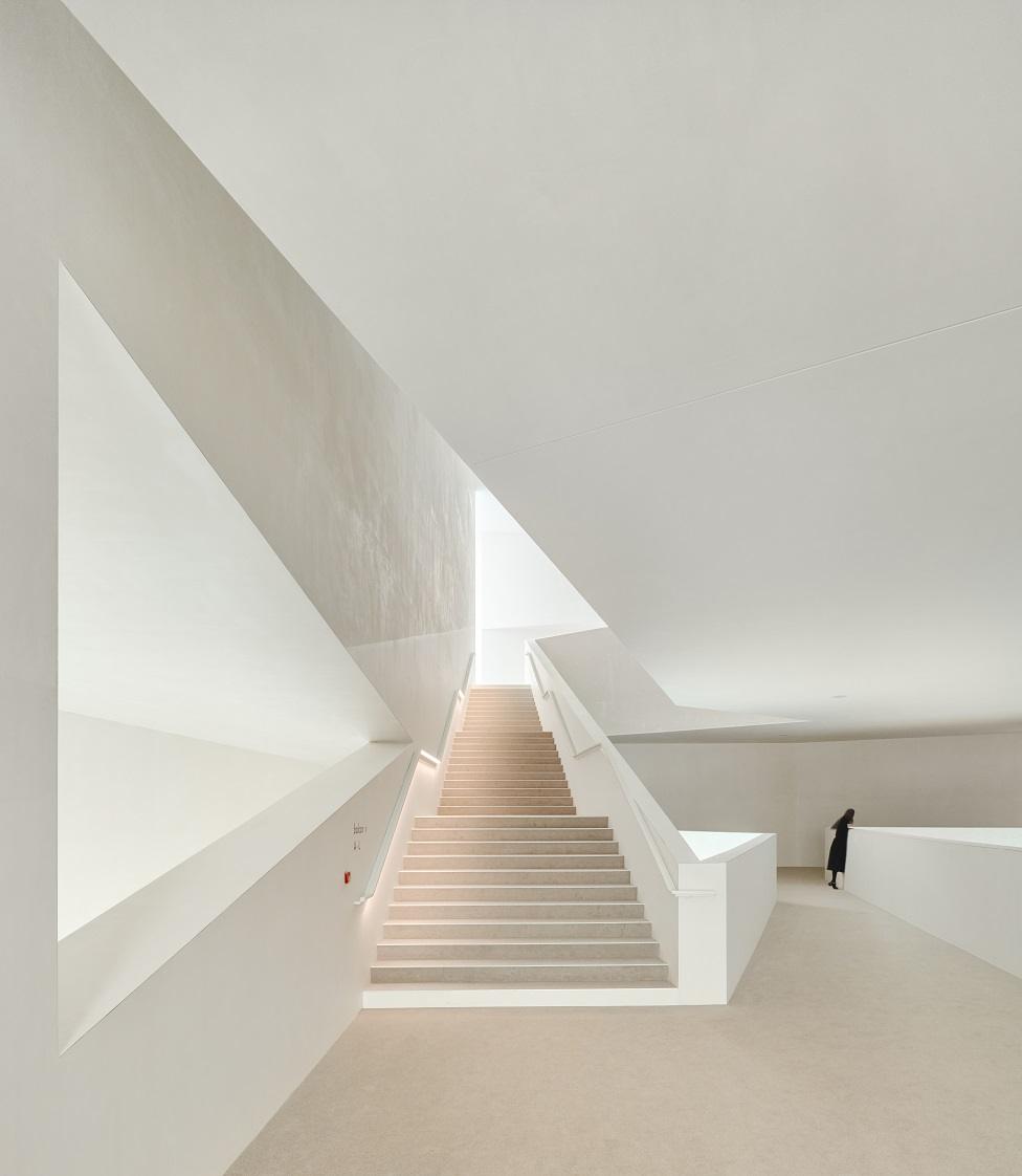 View of bright walls and a staircase with a solitary figure in black