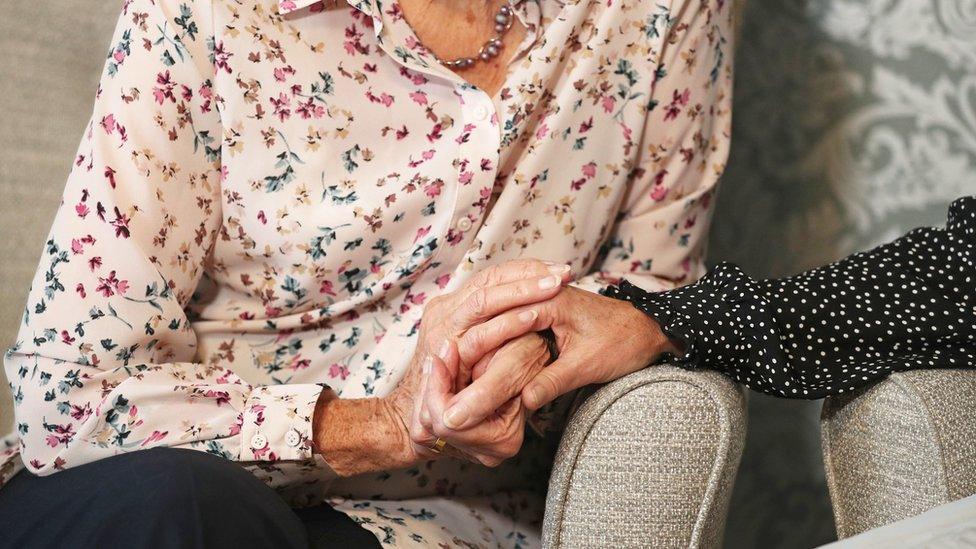 Care home resident holding hands with her daughter