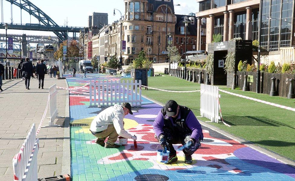 Alex Mulholland and friend painting a mural on a disused bus lane on the Newcastle Quayside