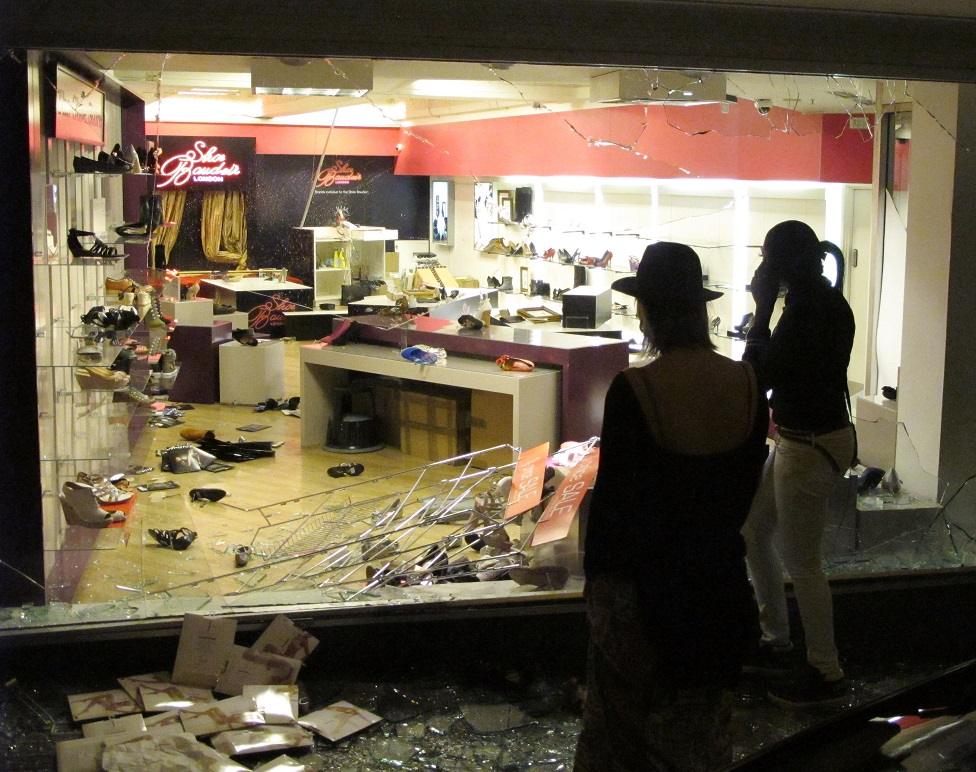 Two women look at a smashed store front