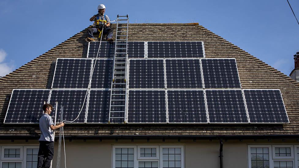 Solar roof fitters construct an array of panels