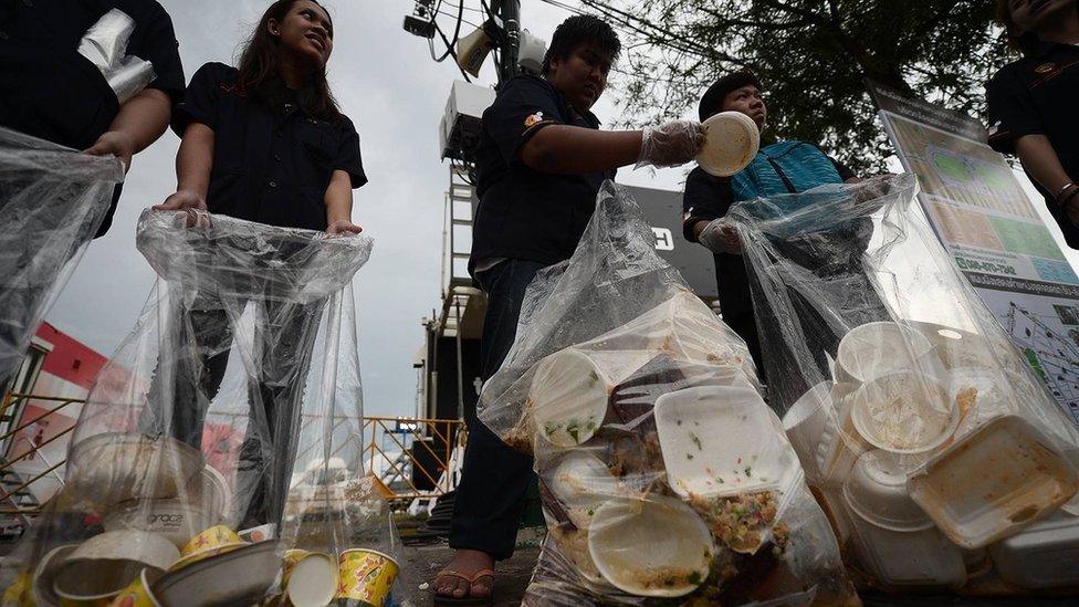 Volunteers stands with rubbish bags near the royal palace in Bangkok