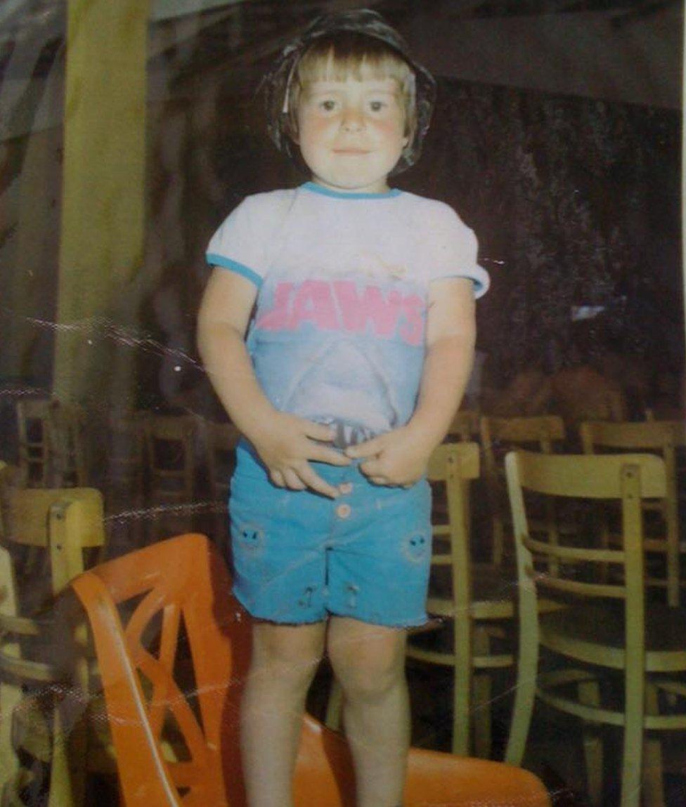 Christopher Higgins standing on a chair, wearing a Jaws T-shirt: caption: "We're going to need a bigger paddling pool"