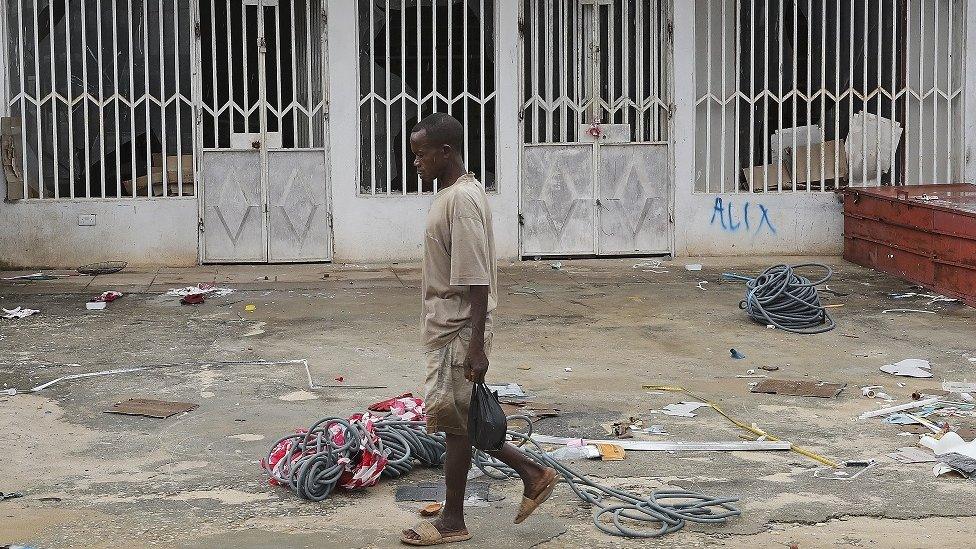 Man walking past a shuttered shop