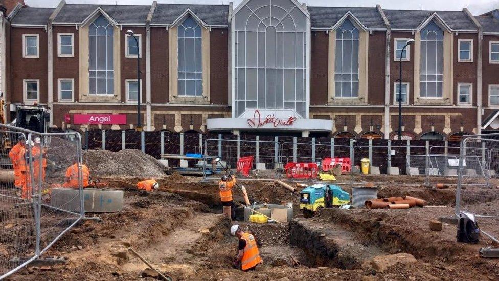 People in hi-viz jackets explore the soil on the site of Northampton market square