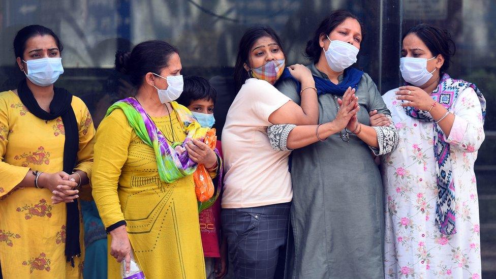 Relatives and family members of a person who died of Covid-19, break down during the cremation