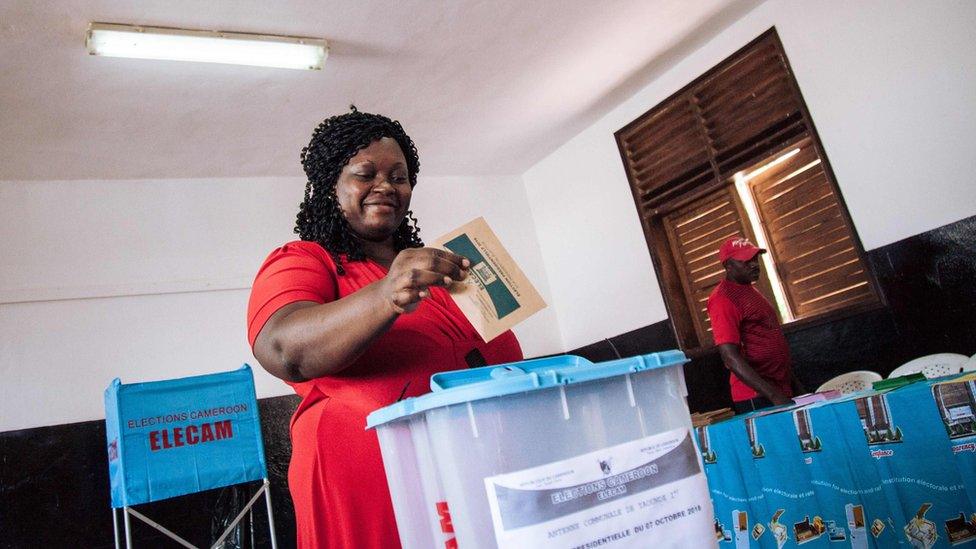 A woman casts her ballot in the polling station where the incumbent President is expected to vote in Bastos neighbourhood in the capital Yaounde