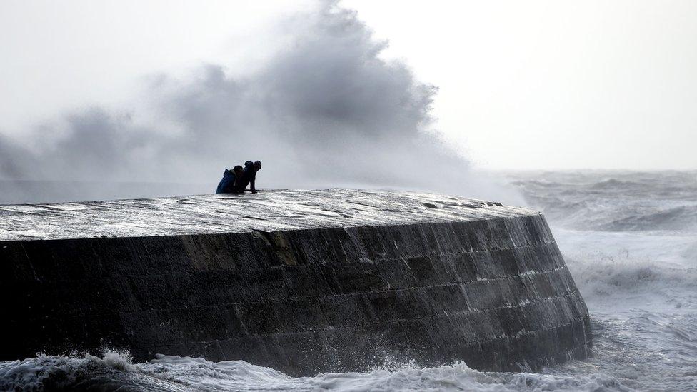 People watch as waves crash over the Cobb at Lyme Regis, Dorset