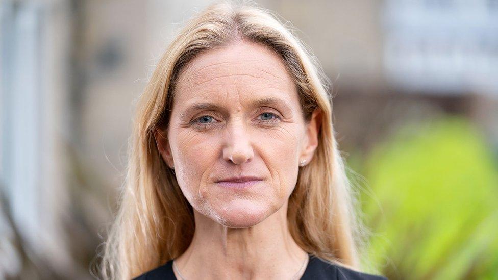 Labour MP Kim Leadbeater looks straight at the camera, in front of a blurred background. She has long blond hair, and is wearing a black top.