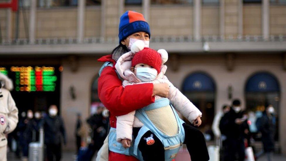 Passengers, wearing protective facemasks, start to arrive from the provinces at the Beijing Railway Station on January 30, 2020