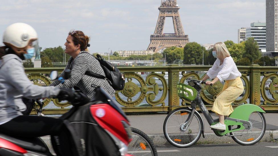 A woman wears a protective face mask while cycling across Pont Mirabeau bridge, near the Eiffel Tower