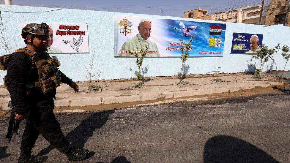 An Iraqi policeman walks next to posters of Pope Francis outside the St Joseph Chaldean Catholic Church in Baghdad's Karada district, Iraq (3 March 2021)