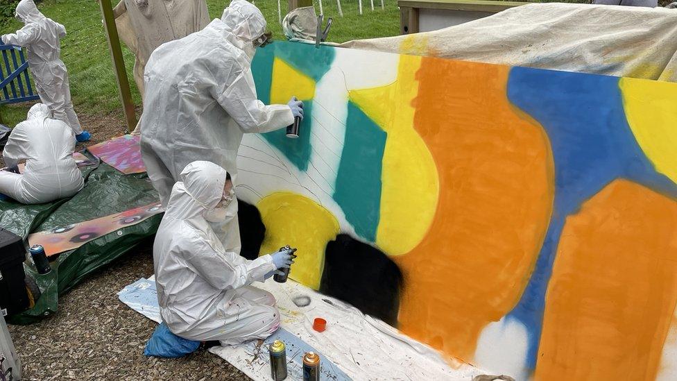 Students spraying paint onto the boards