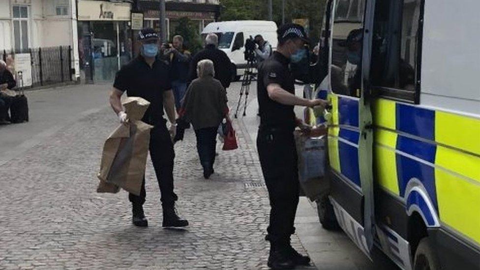 Police carrying evidence bags outside the cafe