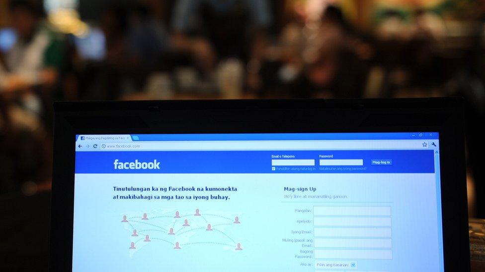 A coffee shop employe walks past a display showing the Tagalog language version of social networking site facebook in Manila on May 15, 2012