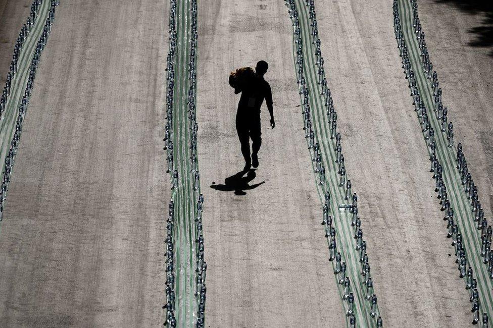 A Muslim volunteer walks past long rows of plastic bottles.