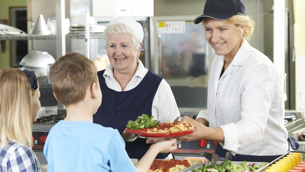 Children being handed school lunches